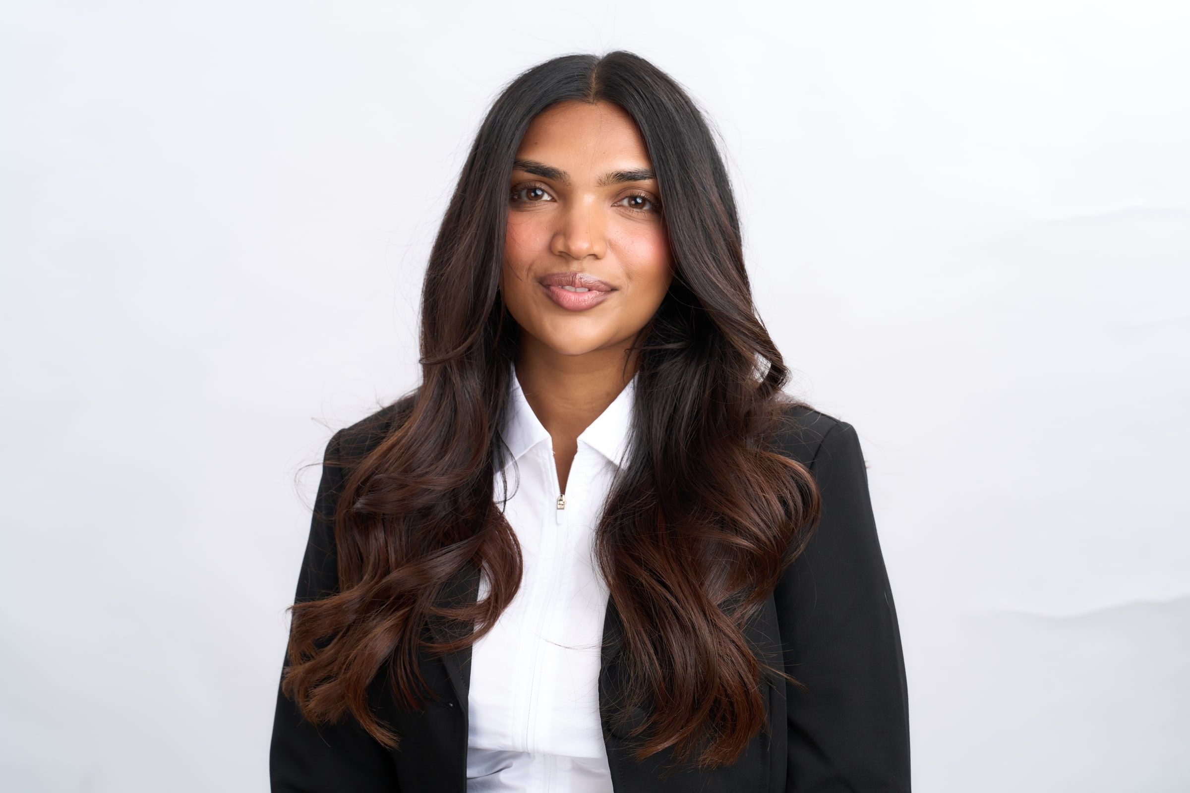 Delcy Pandya in a black blazer and white shirt, looking at the camera.